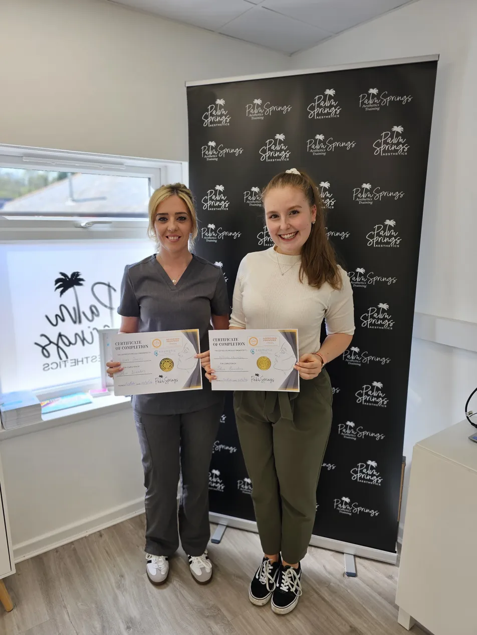 Two graduates holding certificates together